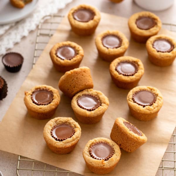 Peanut butter cup cookies arranged on a piece of parchment paper on top of a wire cooling rack.