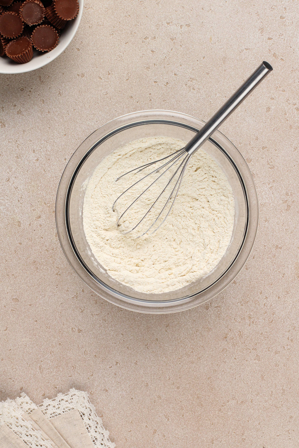 Dry ingredients for peanut butter cookies whisked in a glass mixing bowl.