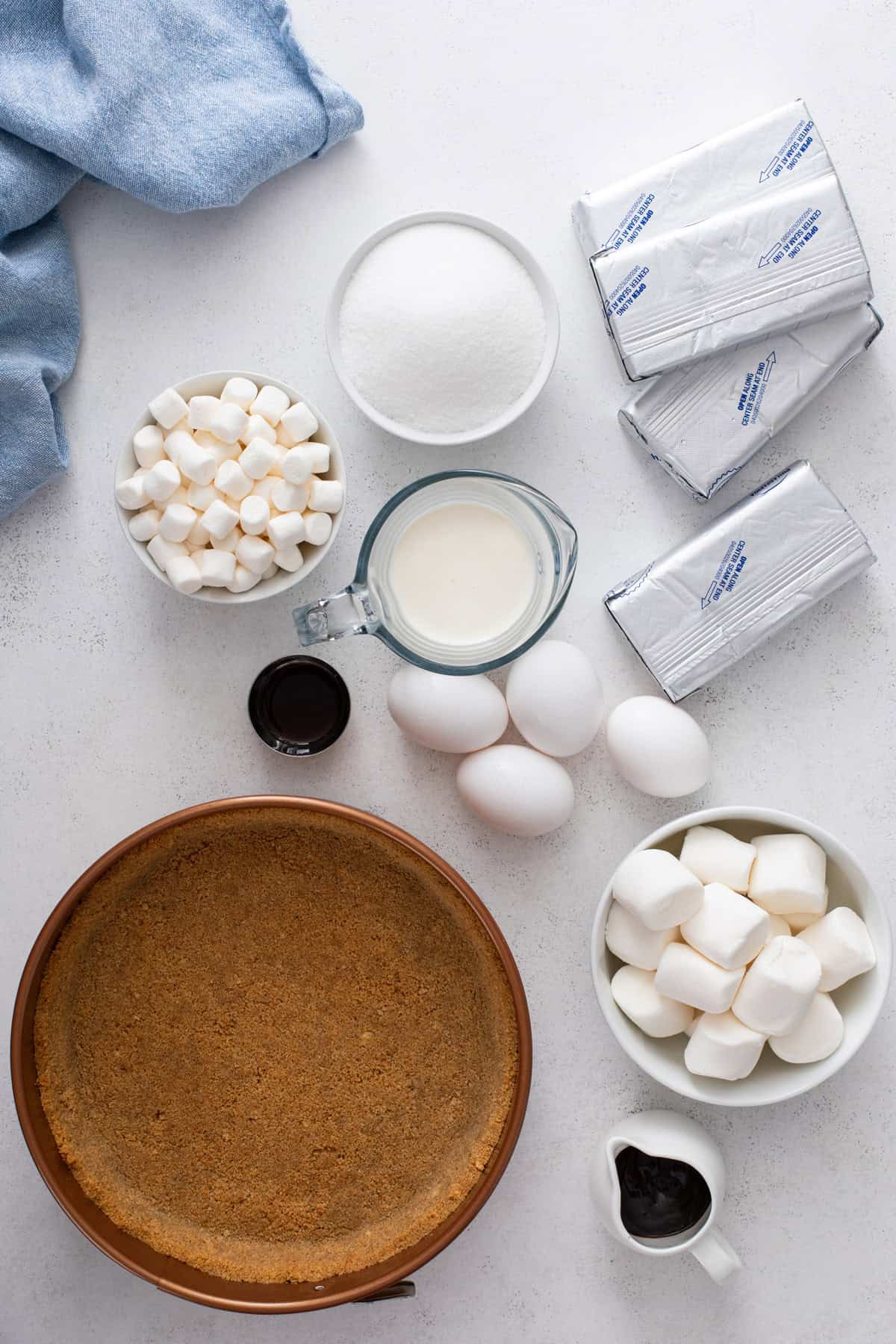 Ingredients for s'mores cheesecake arranged on a countertop.