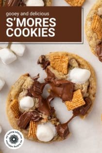 Two halves of a s'mores cookie on a countertop with melty chocolate pulled between the two cookie halves. Text overlay includes recipe name.