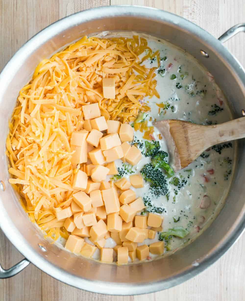 Spoon stirring cheese into a pot of broccoli cheese soup