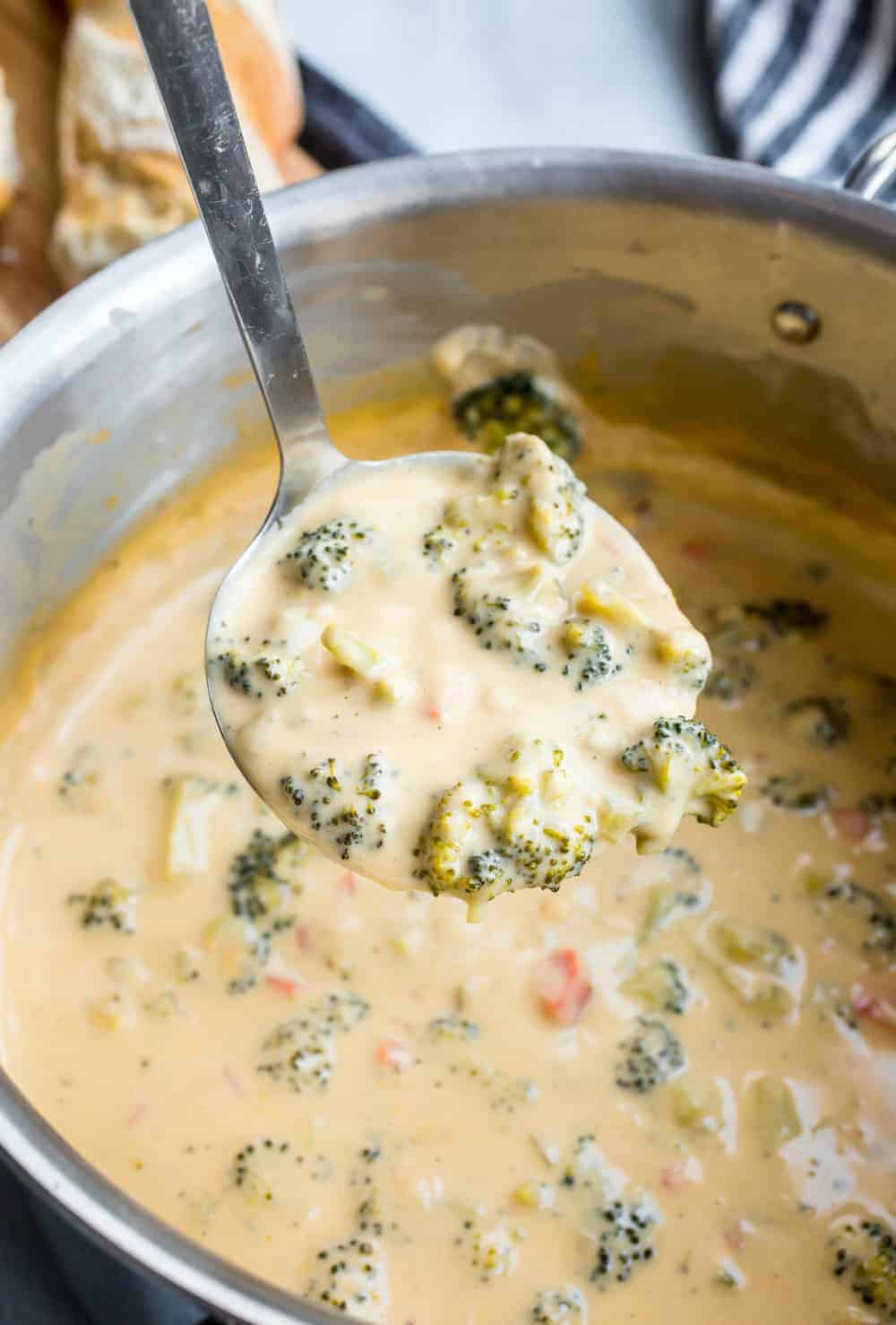 Ladle of broccoli cheese soup over a pot of soup