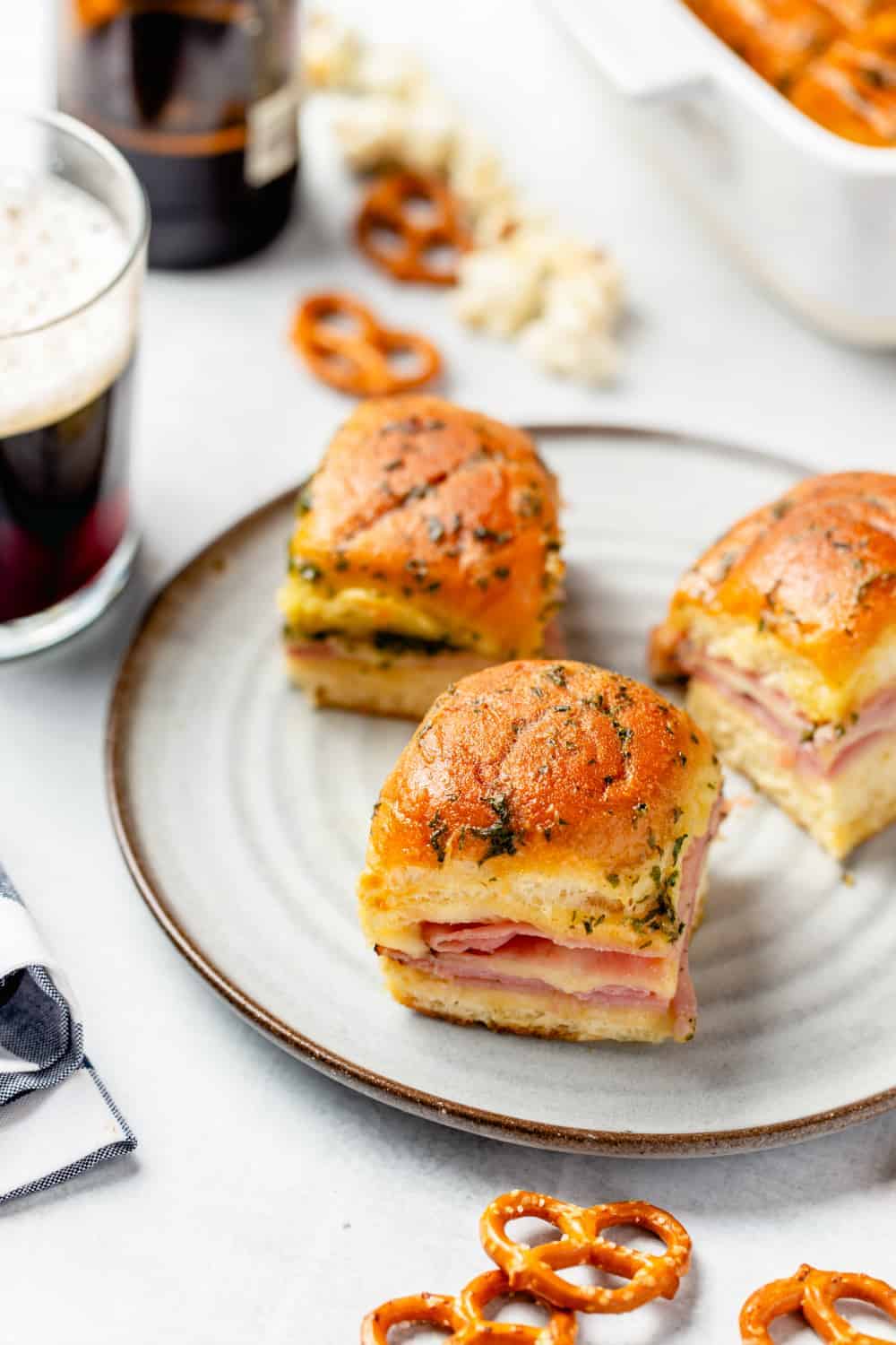 Plate of three ham and cheese sliders next to a glass of beer