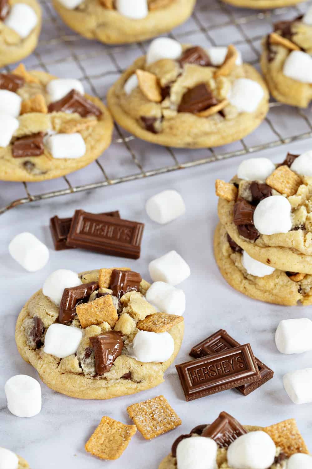 S'mores cookies scattered on a marble surface with mini marshmallows and chocolate pieces