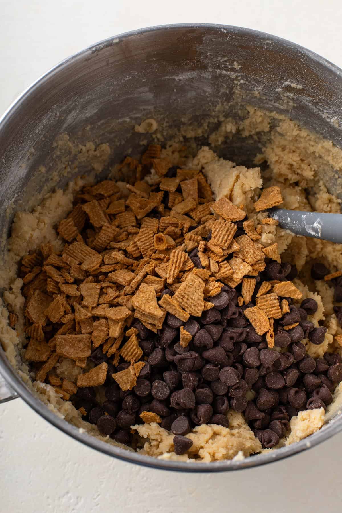Chocolate chips and graham cereal pieces being added to cookie dough.