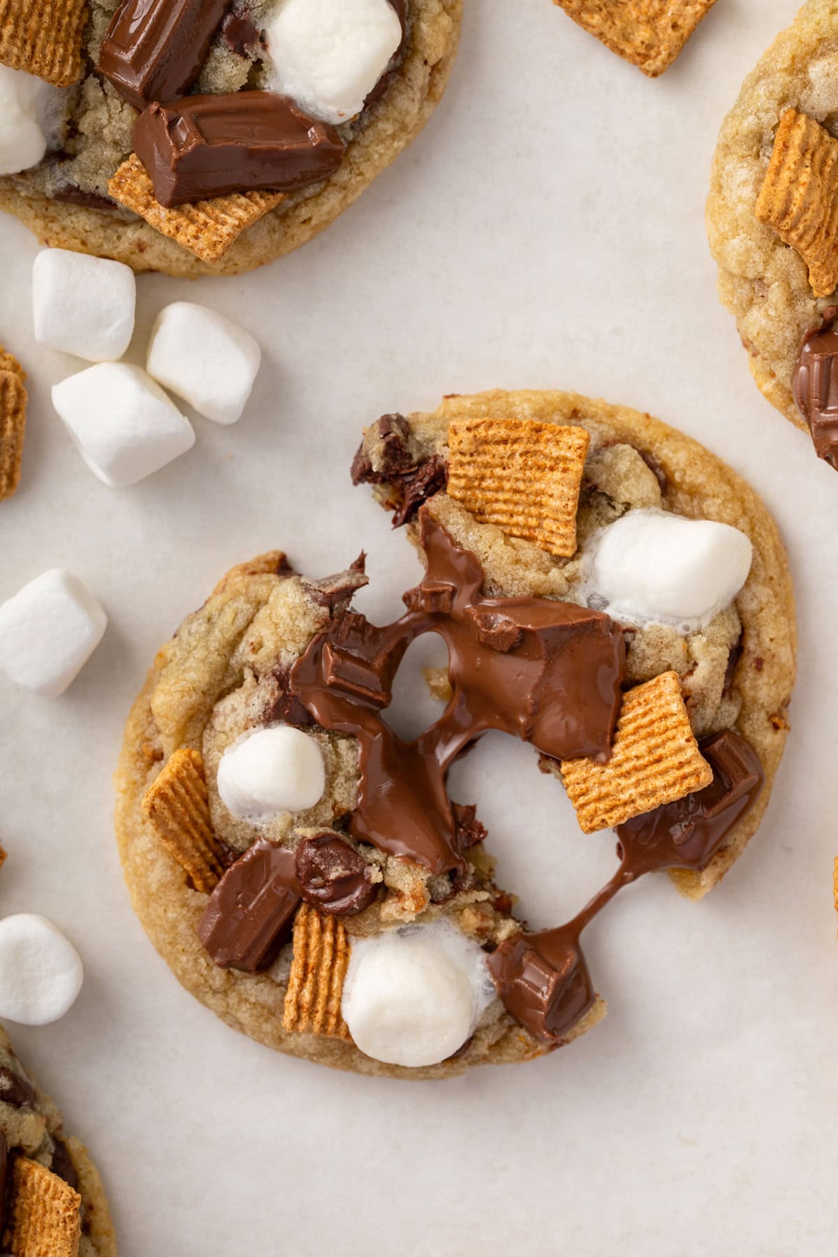 Two halves of a s'mores cookie on a countertop with melty chocolate pulled between the two cookie halves.