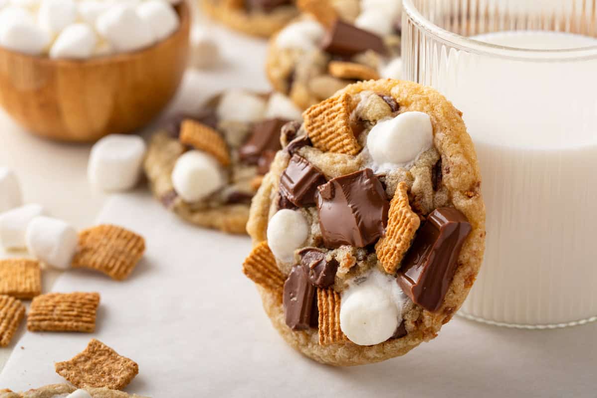 S'mores cookie leaning against a glass of milk on a countertop.