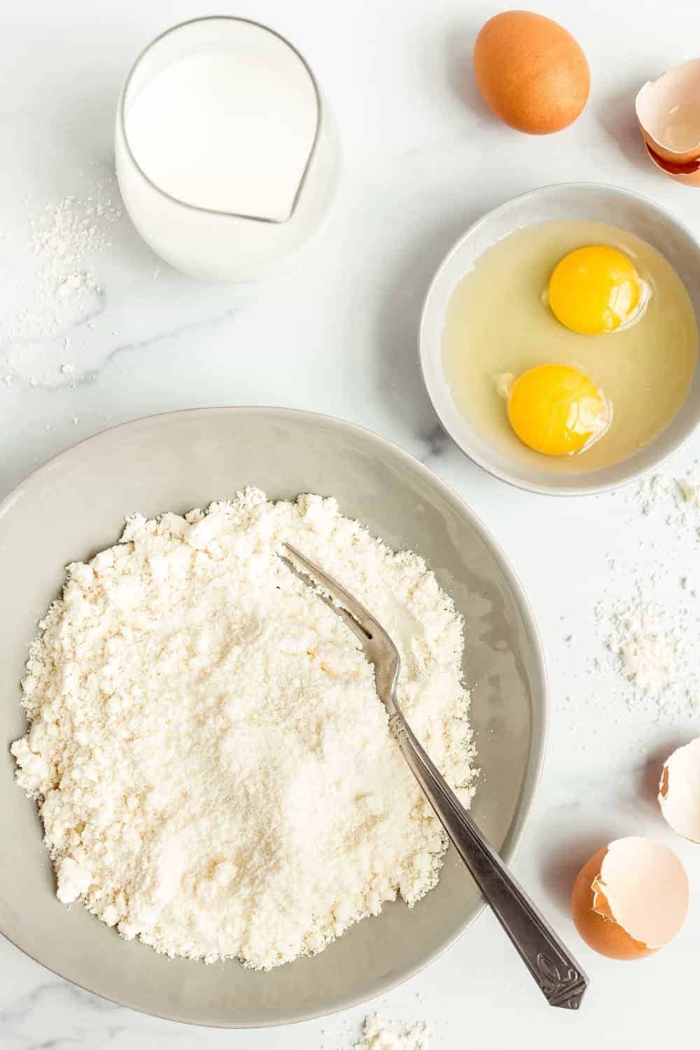 Ingredients for Bisquick pancakes in bowls on a marble counter