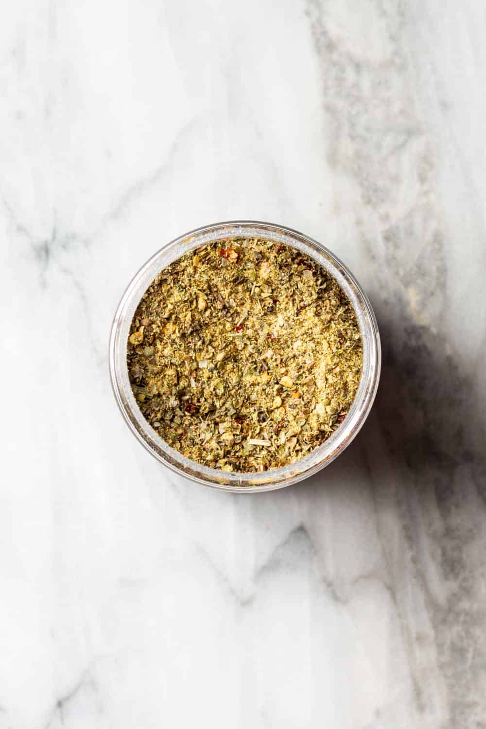 Pizza seasoning for using in homemade meat sauce in a jar on a marble counter