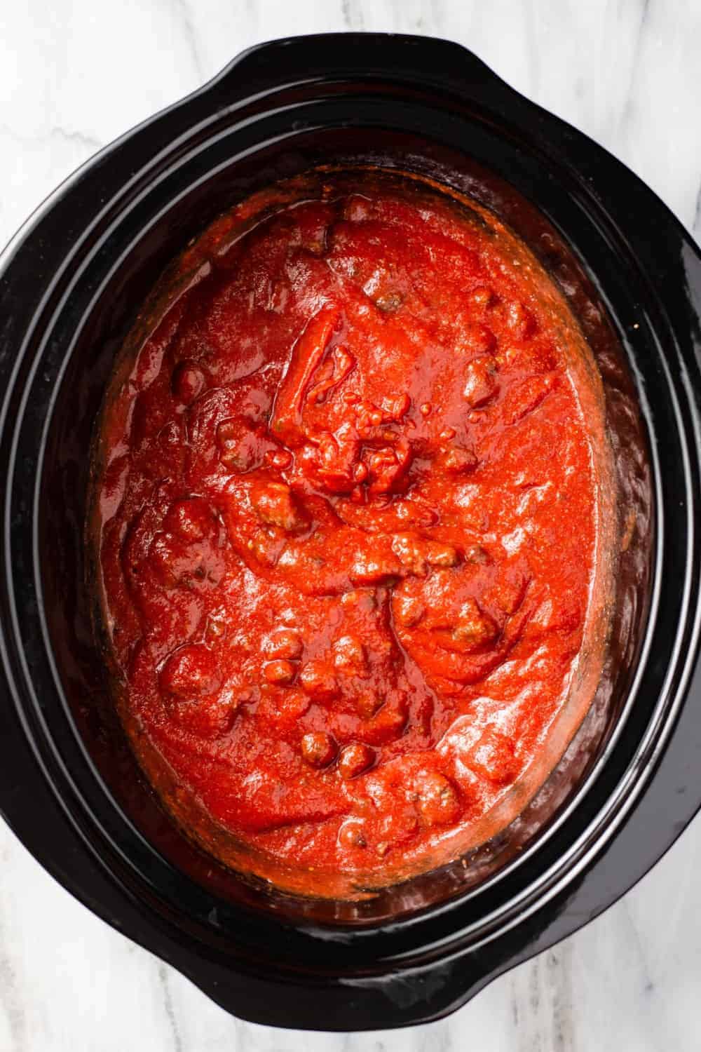 Overhead view of homemade meat sauce in the black crock of a slow cooker