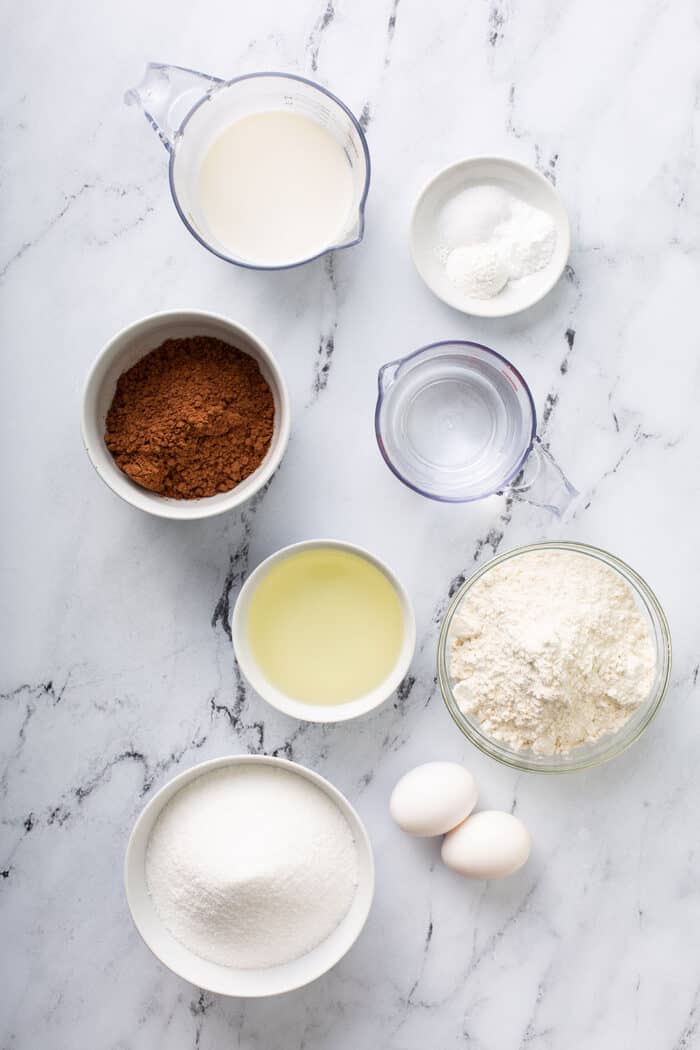 Overhead view of the ingredients for Hershey's chocolate cake in bowls on a marble counter