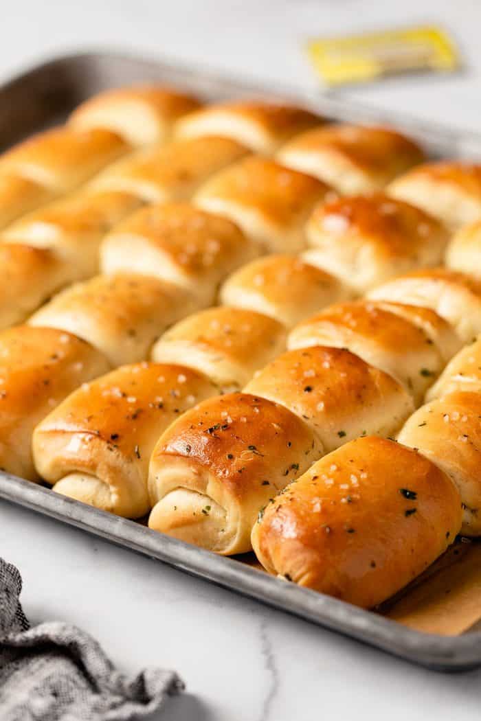 Close up of freshly baked garlic and herb parker house rolls on a sheet pan