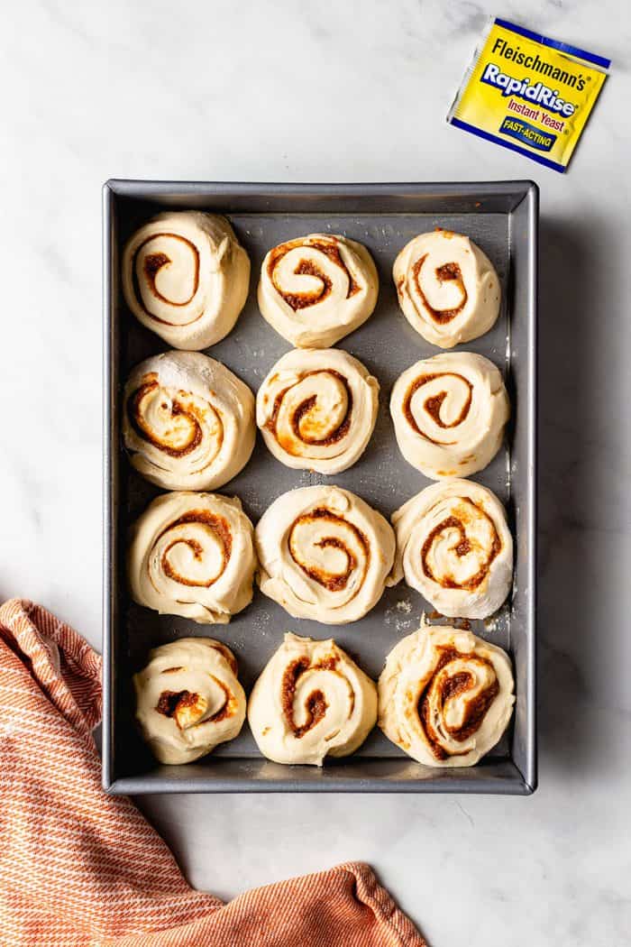 Overhead view of pumpkin spice cinnamon rolls in a baking dish before rising