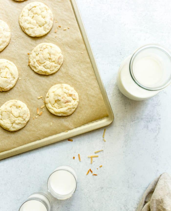 Overhead view of a cookie sheet with chewy lime sugar cookies next to a glass of milk