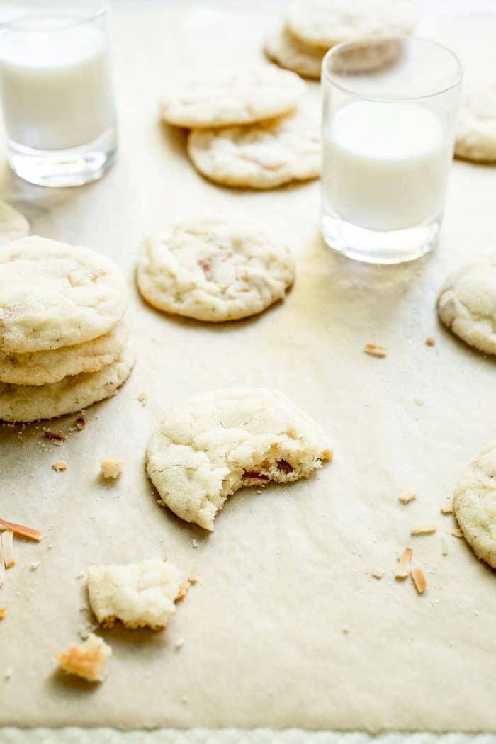 Chewy lime sugar cookies scattered on a counter among glasses of milk