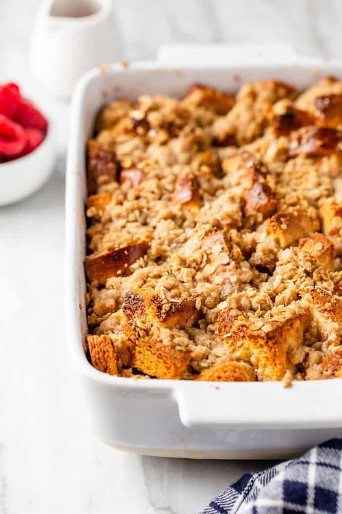 Close up view of freshly baked overnight french toast casserole in a white baking dish set on a marble countertop