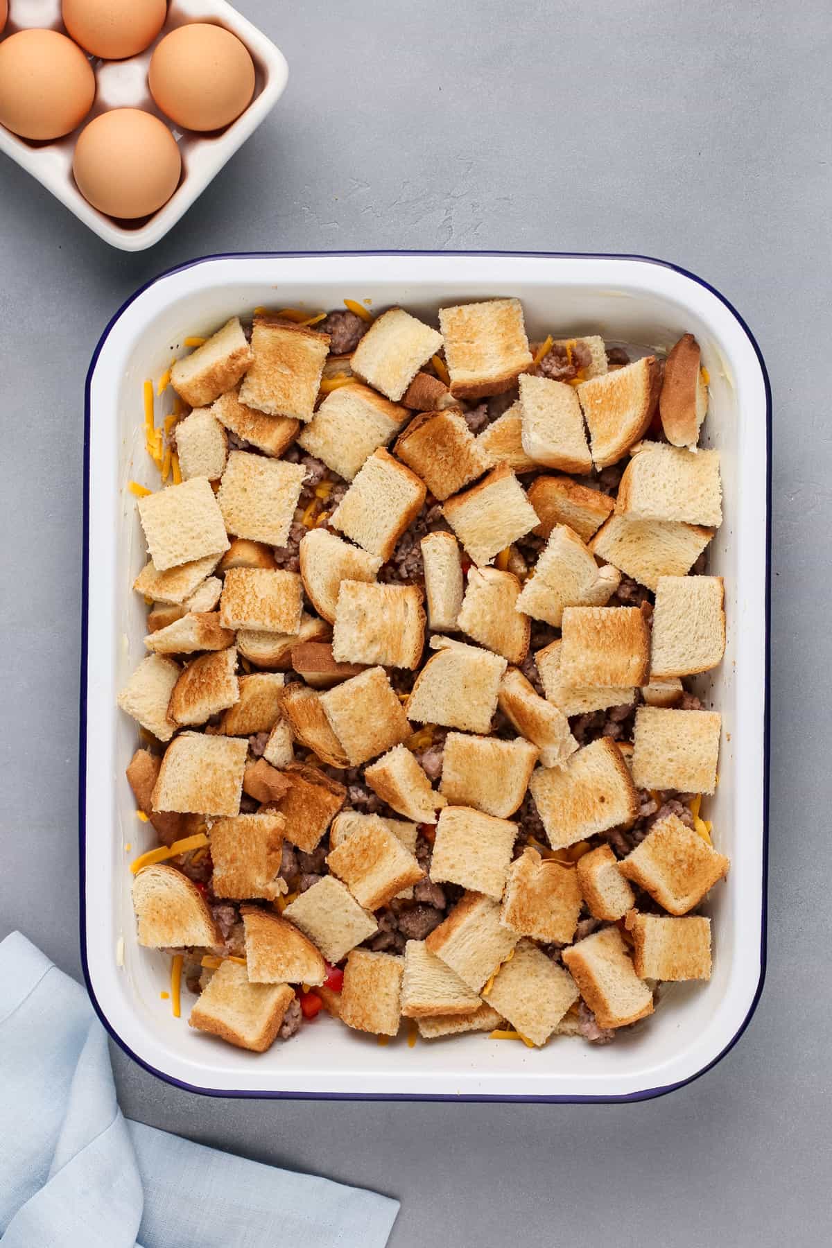 Toasted cubed bread layered in a baking dish.
