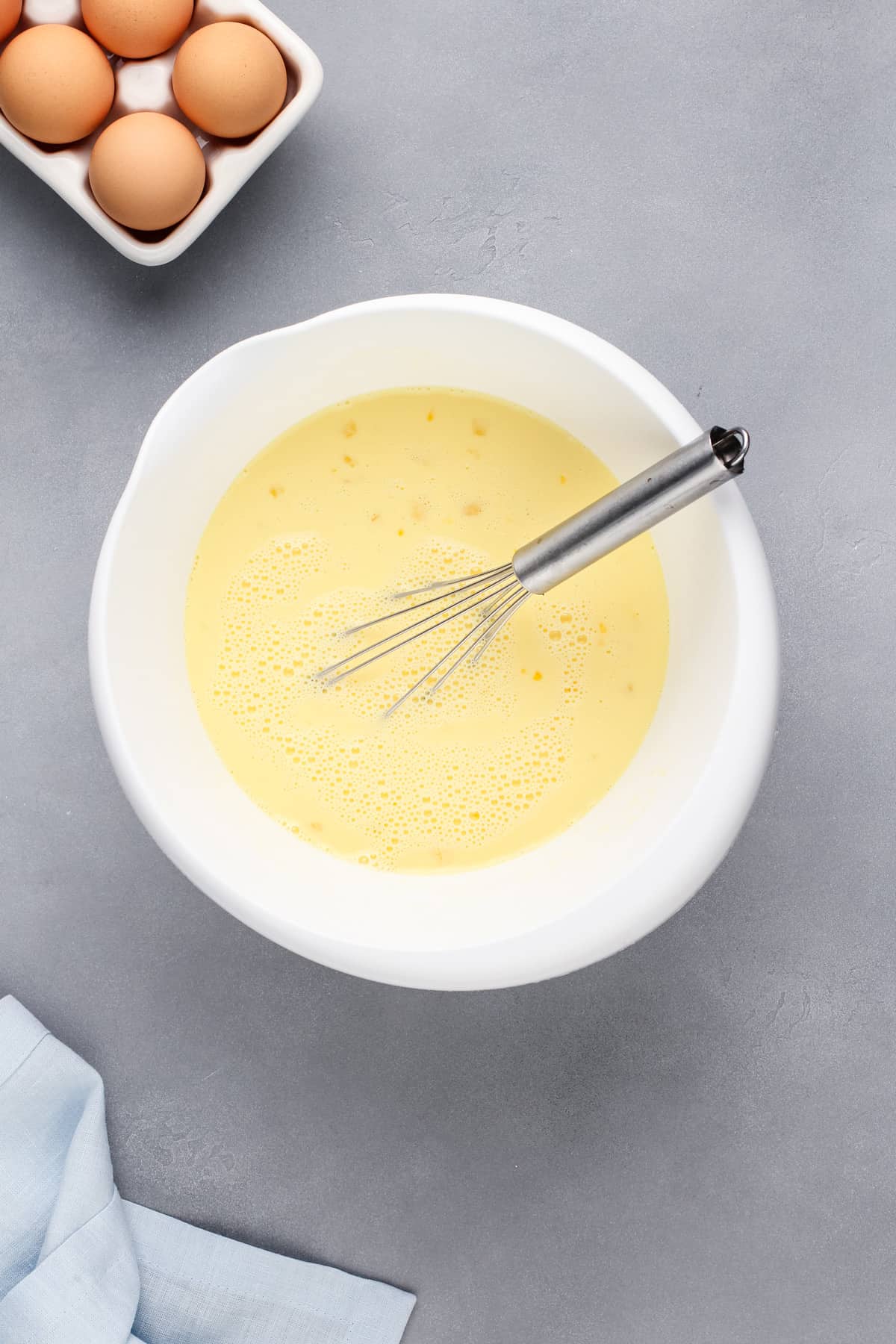 Eggs and milk whisked in a large mixing bowl.