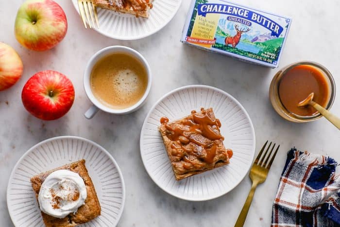 Overhead view of apples bars plated on white plates, surrounded by coffee and a package of butter