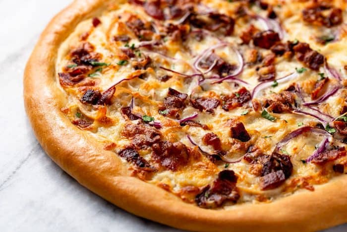 Unsliced chicken bacon ranch pizza set on a marble surface