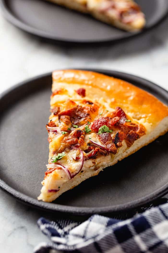 Slice of chicken bacon ranch pizza on a black plate