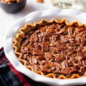 Baked chocolate pecan pie in a white pie plate on top of a plaid towel