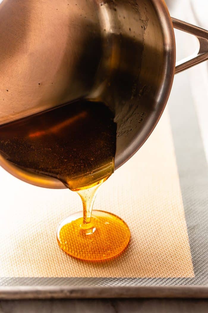 Pan pouring cooked caramel onto a piece of parchment