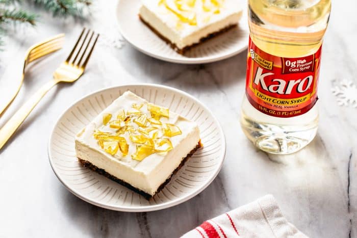 No-bake cheesecake bar on a white plate with a second bar and a bottle of corn syrup in the background