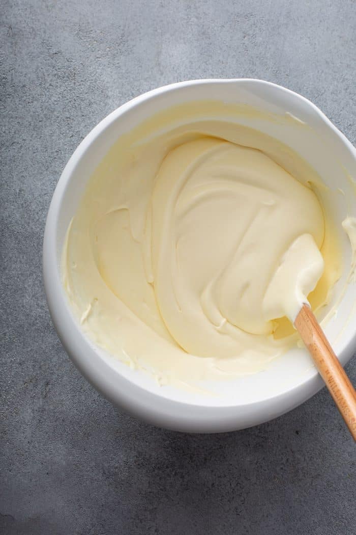 Spatula stirring the filling for banana cream pie eclair cake in a white bowl