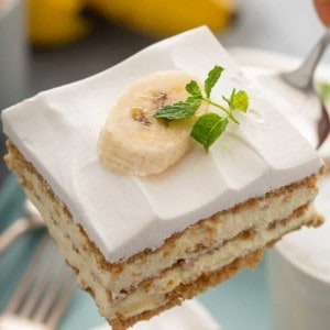 Cake server holding up a slice of banana cream pie eclair cake, showing the layers