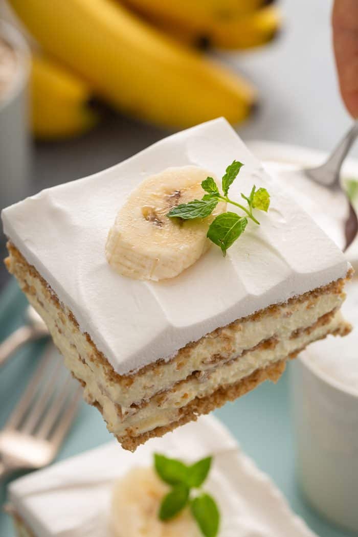 Cake server holding up a slice of banana cream pie eclair cake, showing the layers