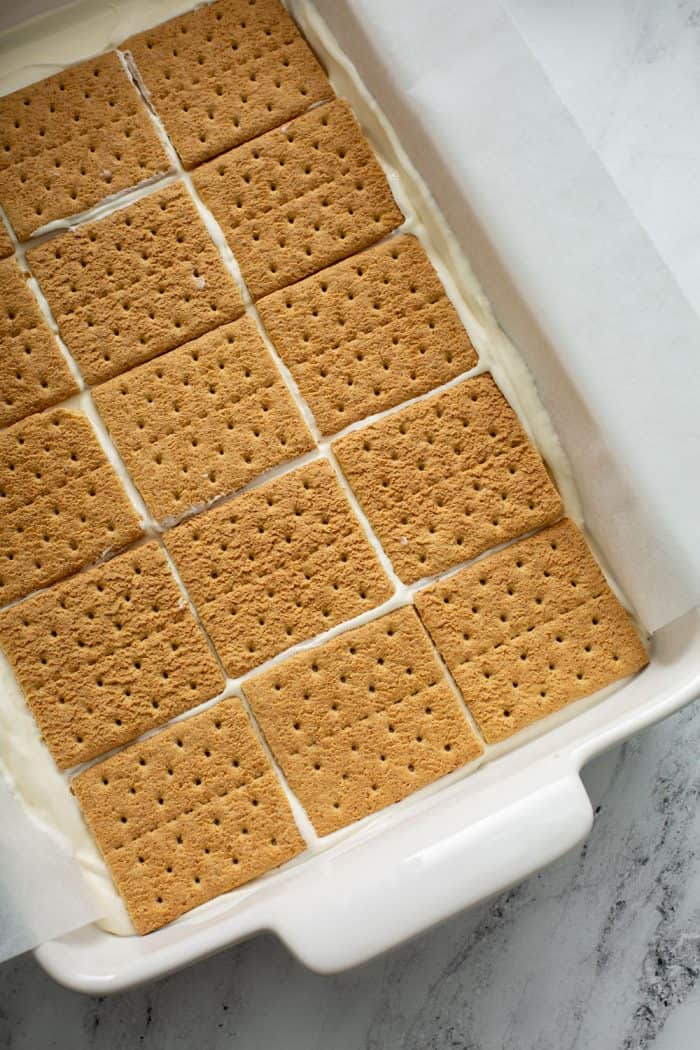 Overhead view of assembled cheesecake eclair cake in a white cake pan