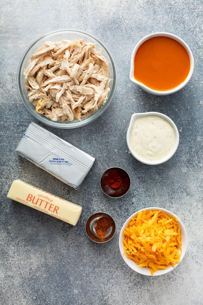 Overhead view of the ingredients for buffalo chicken dip arranged on a concrete counter