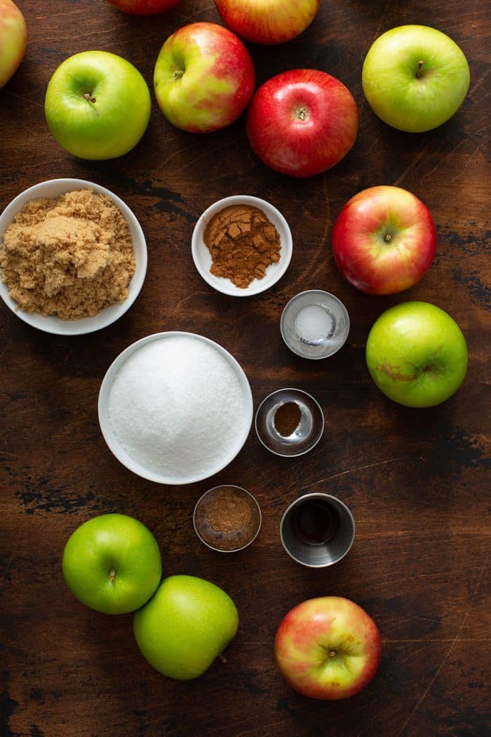 Overhead view of whole apples and the spices for Instant Pot apple butter arranged on a wooden board