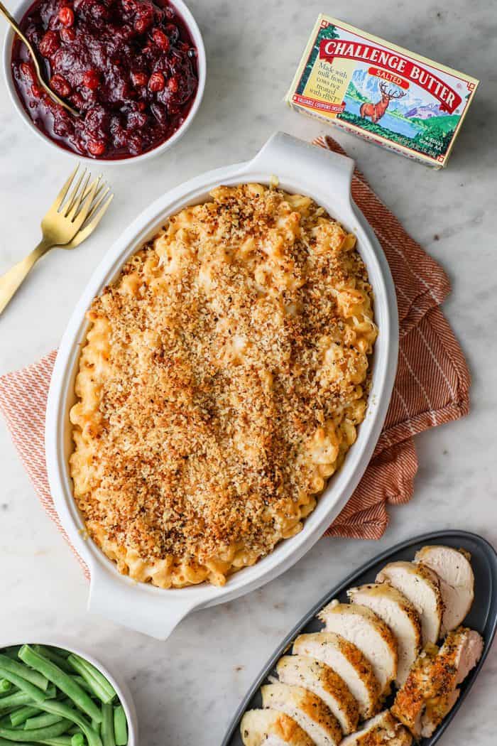 Casserole dish of baked macaroni and cheese on a table next to other Thanksgiving sides