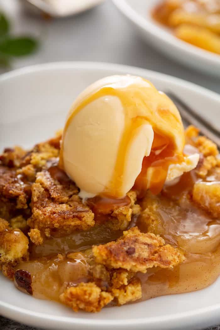 Close up of plated apple dump cake topped with vanilla ice cream and caramel sauce