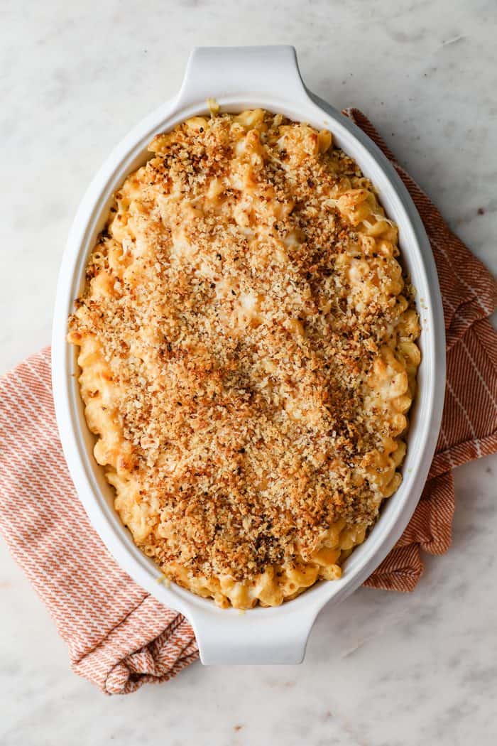 White casserole dish of baked macaroni and cheese on a marble counter