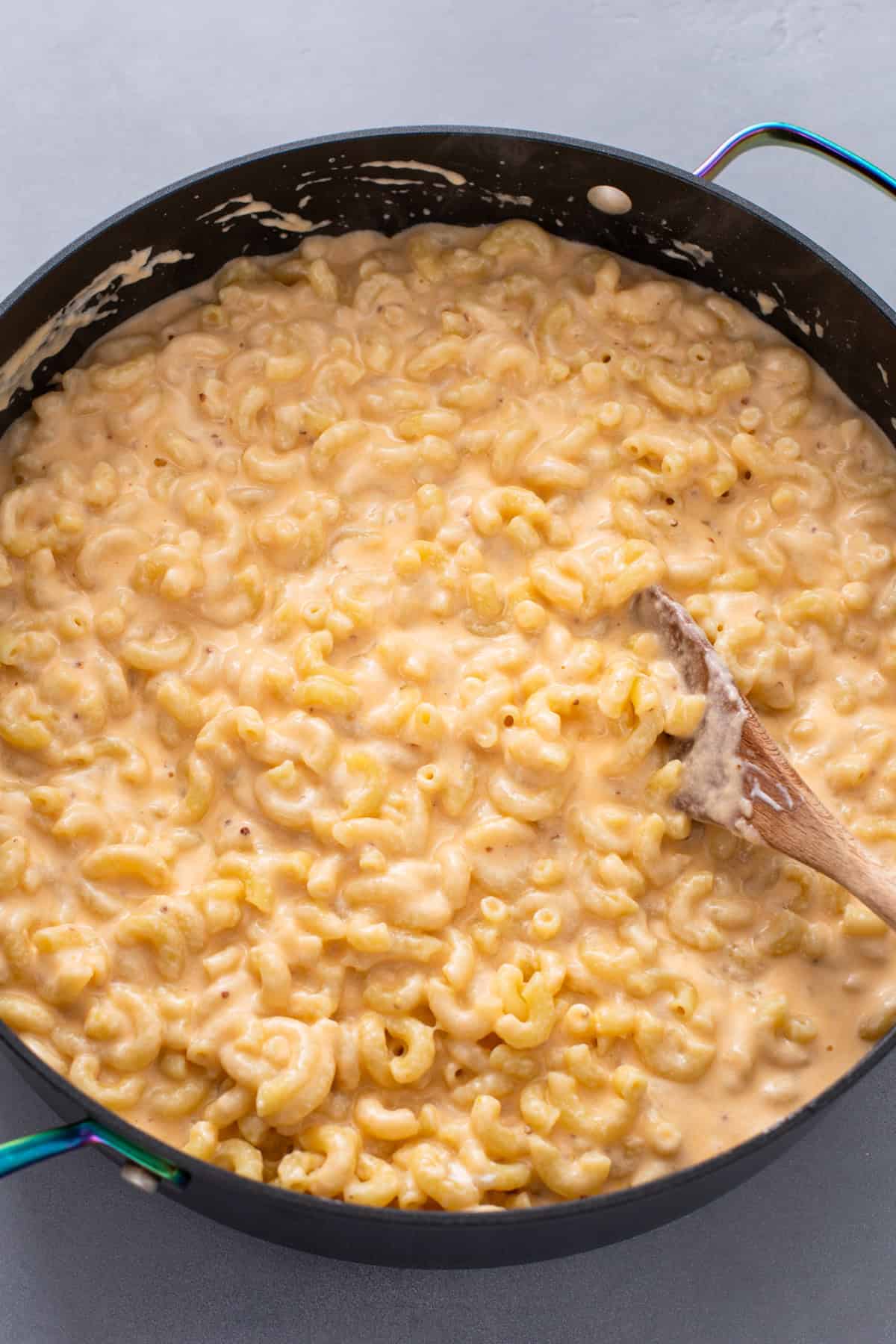 Cooked elbow macaroni mixed with cheese sauce in a skillet.