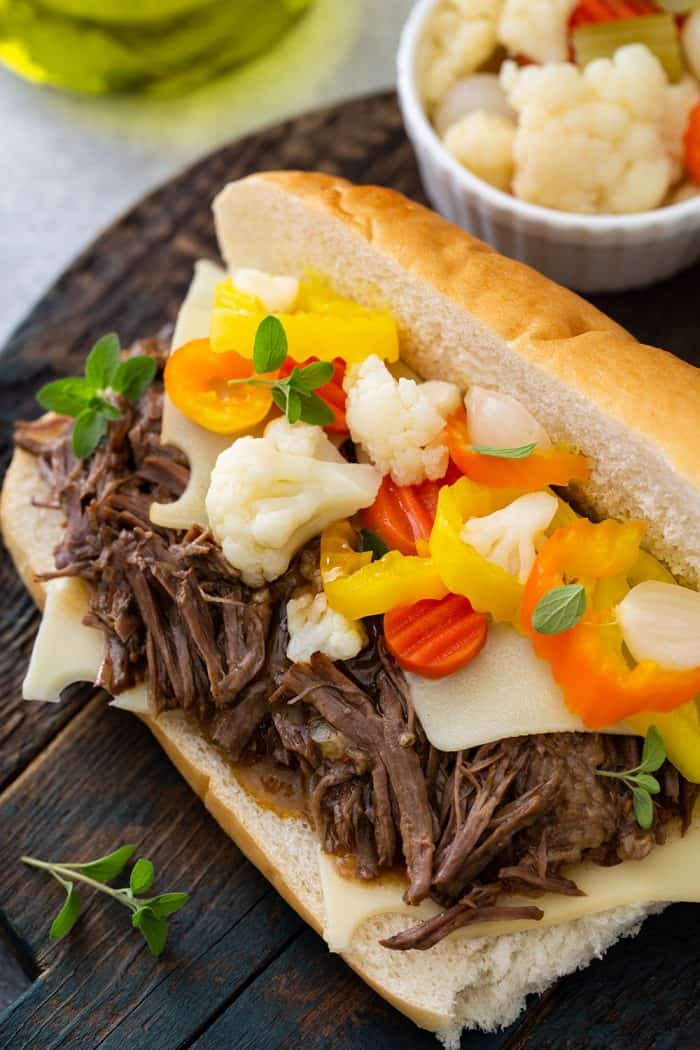 Close up of italian beef on a hoagie roll topped with giardiniera