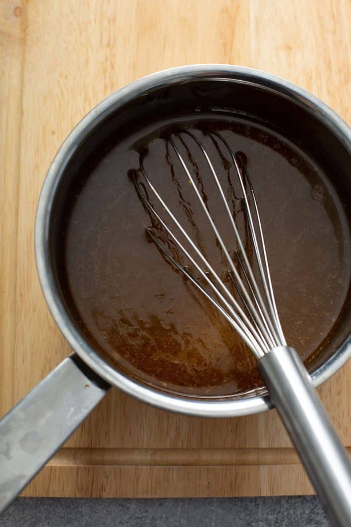 Whisk stirring au jus in a silver saucepot