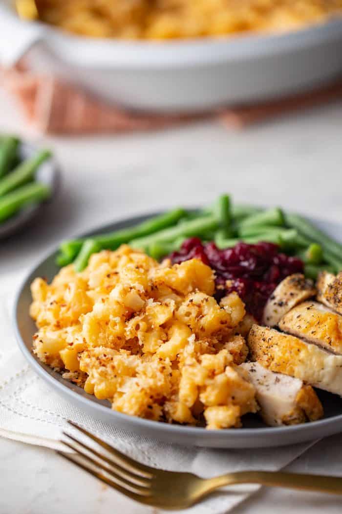 Close up of baked macaroni and cheese on a plate with other Thanksgiving sides