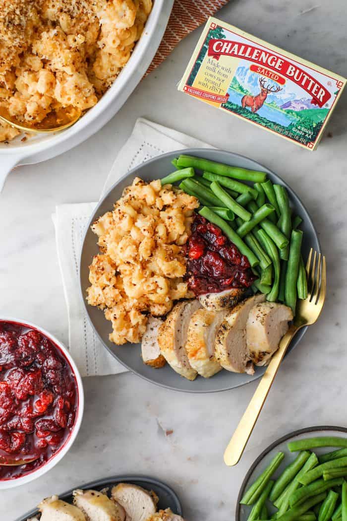 Overhead view of thanksgiving table with a plate full of baked macaroni and cheese and other thanksgiving sides in the center