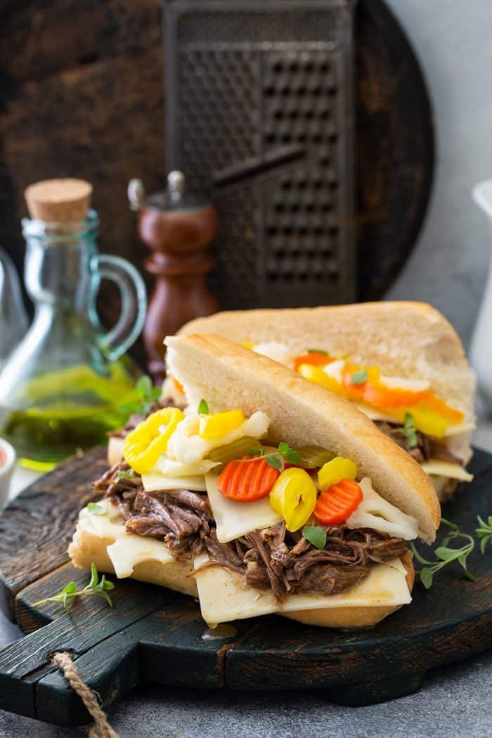 Two assembled Italian beef sandwiches on a wooden board