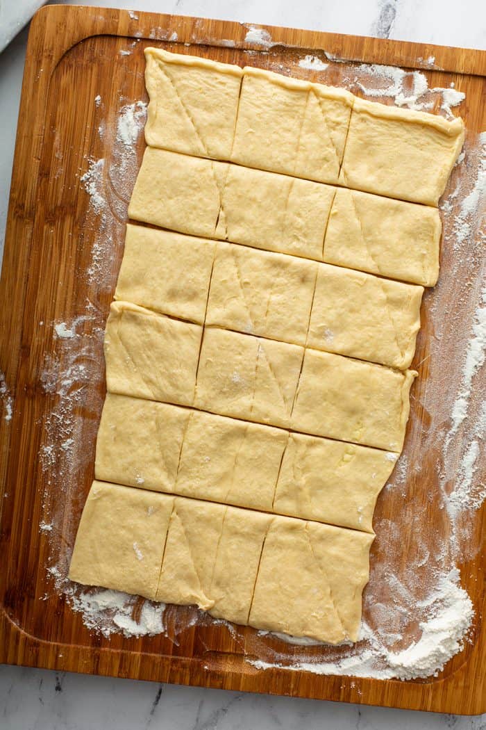 Crescent roll dough rolled out and cut into portions on a cutting board