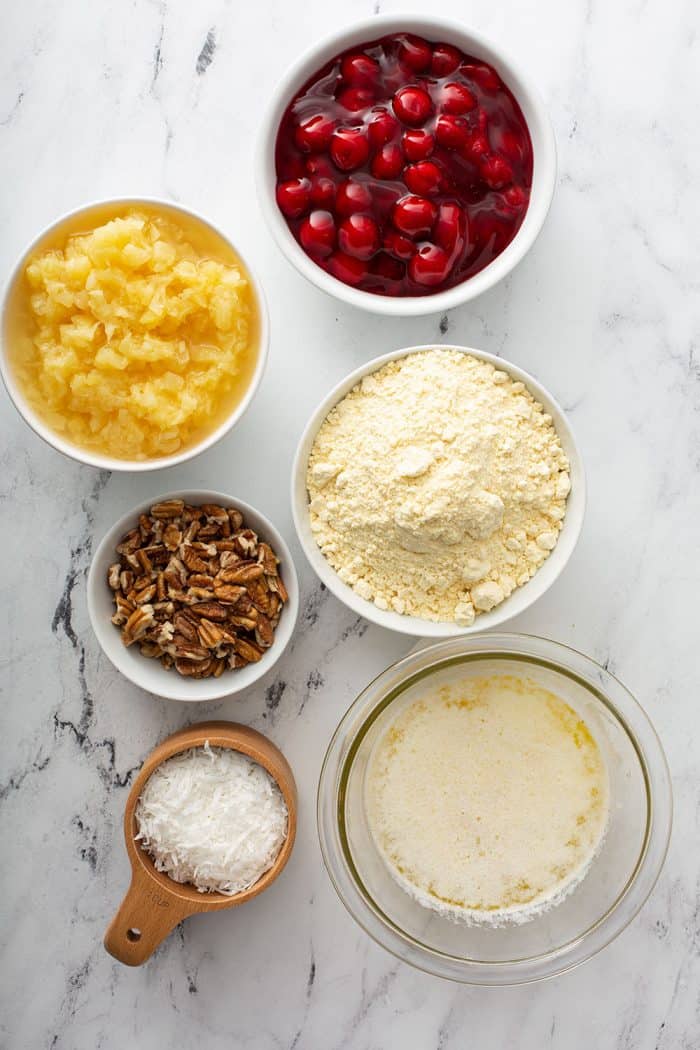 Ingredients for cherry pineapple dump cake on a marble countertop