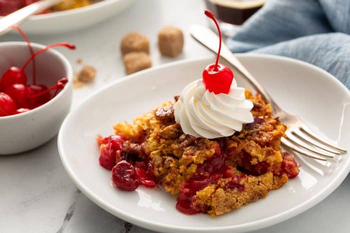 Plated cherry pineapple dump cake topped with whipped cream and a cherry