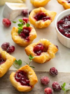 Cranberry brie bites scattered on a marble board