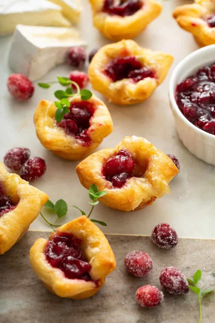 Cranberry brie bites scattered on a marble board