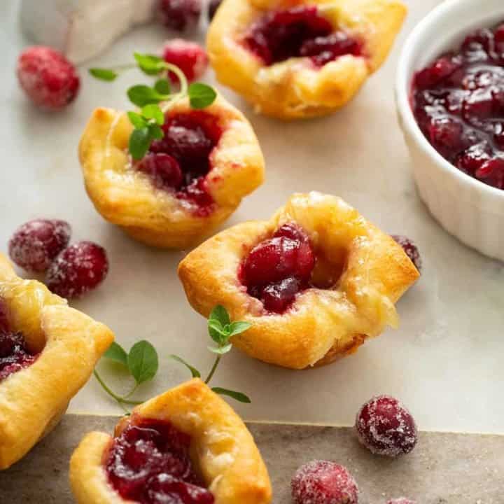 Cranberry brie bites scattered on a marble board