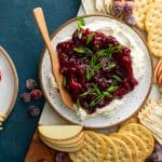 Cranberry cream cheese dip on a platter next to crackers and sliced apples